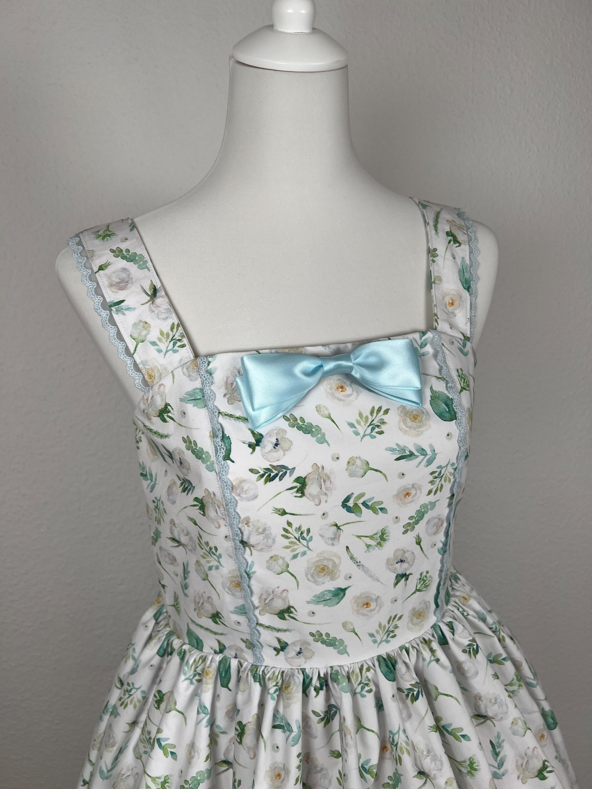 Detailansicht Vorderteil, blaue Schleifenbrosche aus Satinband, blaue Spitze an Teilungsnaht Vorderteil und Trägern