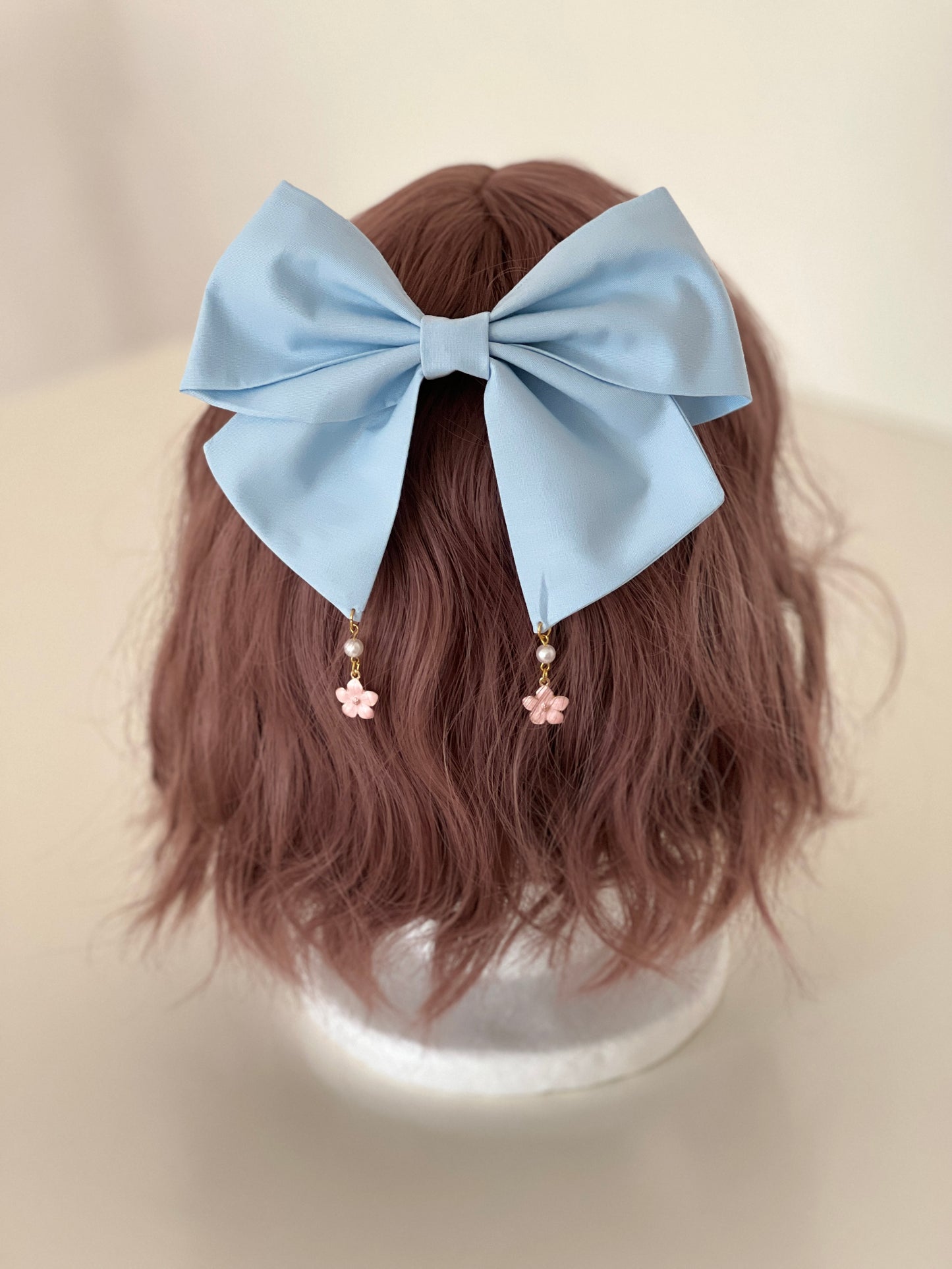 hellblaue Haarschleife mit Anhängern in Kirschblütenform auf Perückenkopf