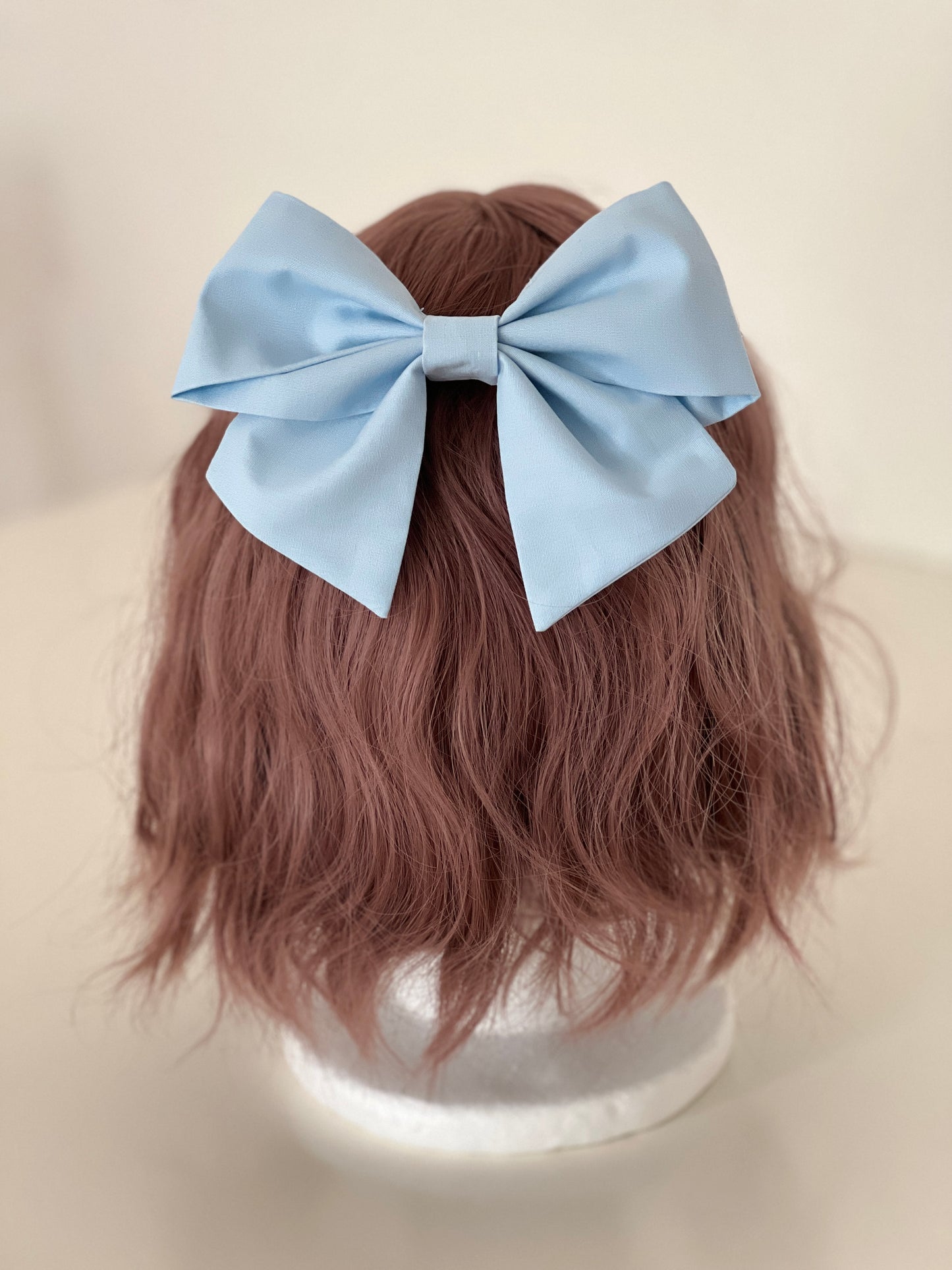 hellblaue Haarschleife auf Perückenkopf
