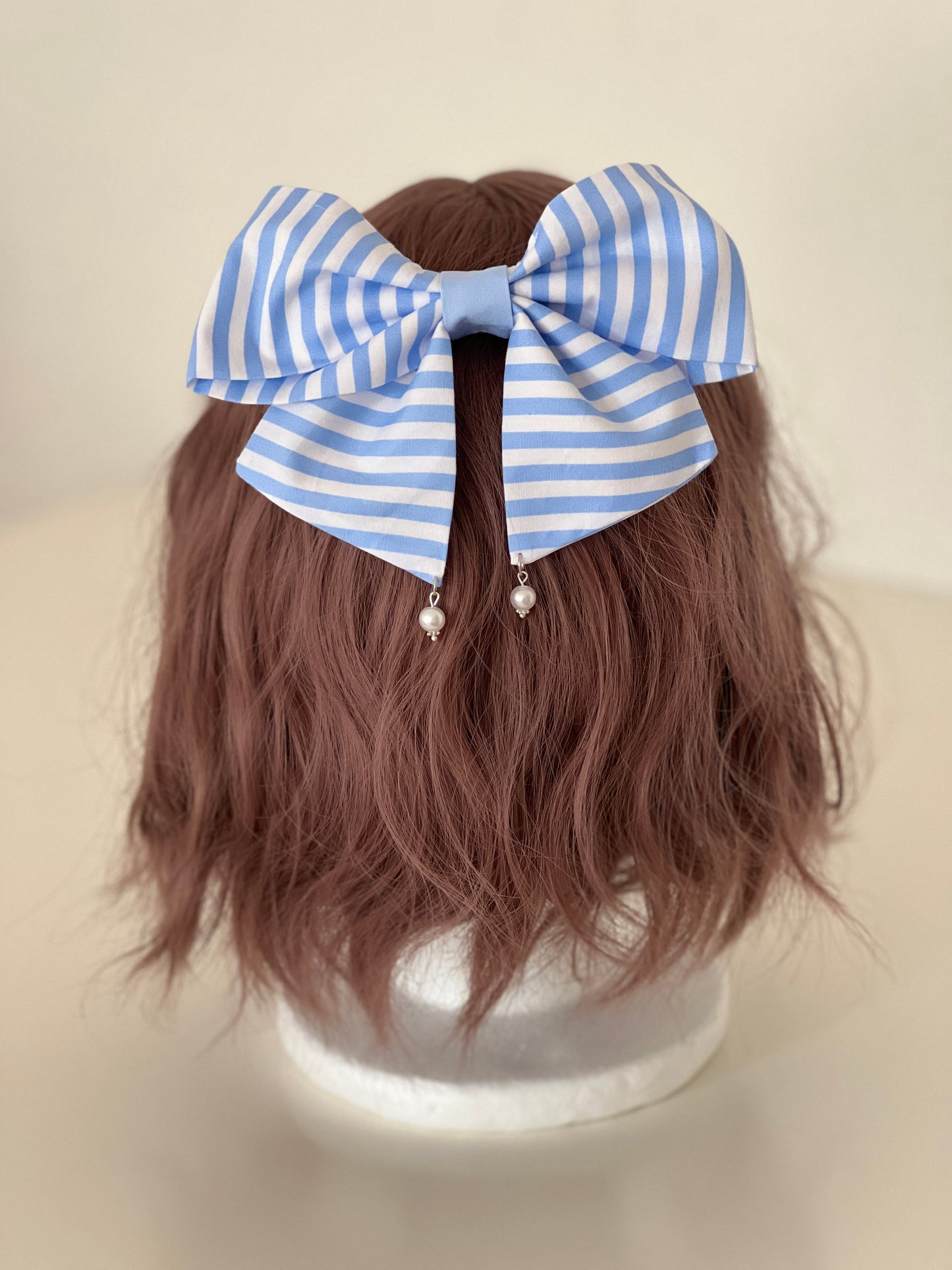 gestreifte Haarschleife in hellblau und weiß mit Perlenanhängern auf Perückenkopf