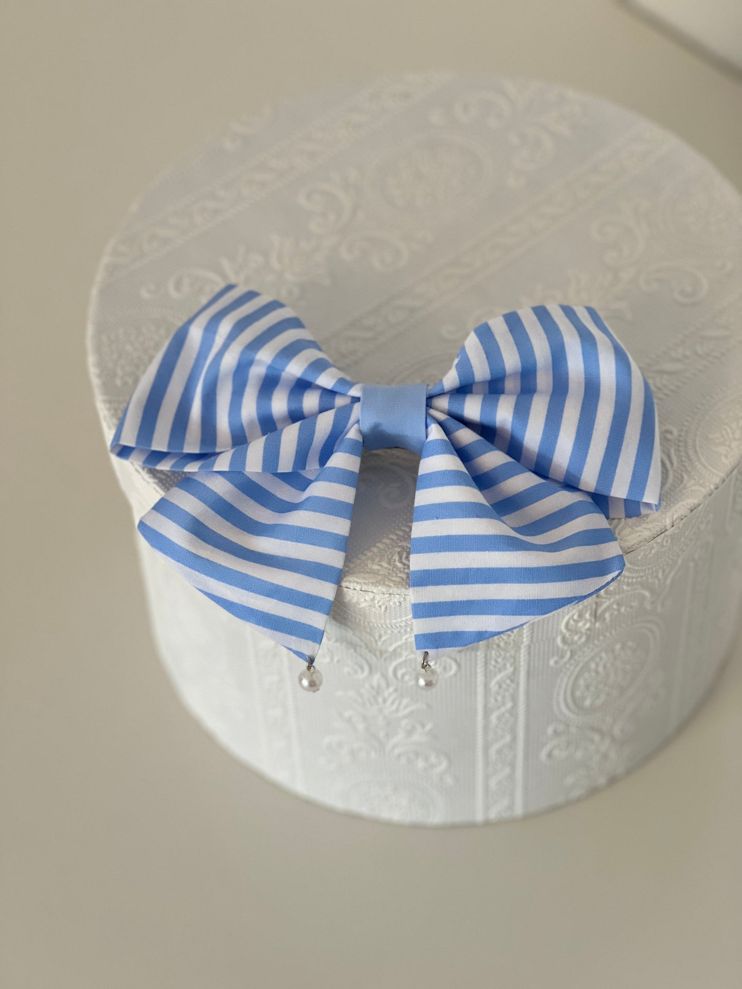 gestreifte Haarschleife in hellblau und weiß mit Perlen, flachliegend 