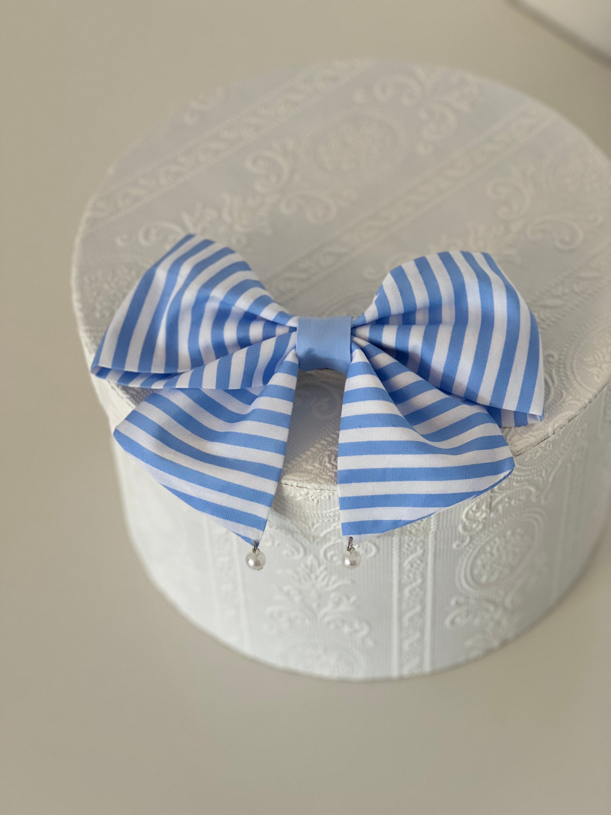 gestreifte Haarschleife in hellblau und weiß mit Perlen, flachliegend 